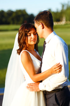 Lovely wedding couple at sunset. Bride, groom in wedding attire with bouquet of flowers. Romantic.の写真素材