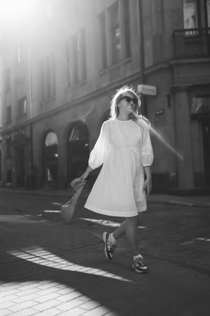 Young woman in white dress walks through streets of city. Lifestyle, travel and vacation conceptの写真素材