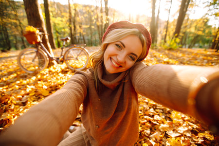 Beautiful girl makes a selfie in the autumn park.の写真素材