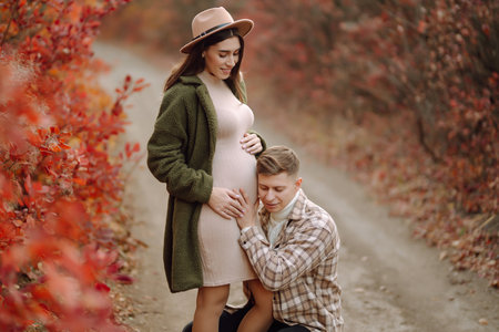 Young pregnant couple in love walking in the park on a autumn day. enjoying time together.の写真素材