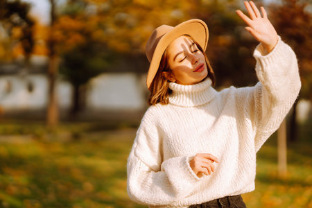 autumn woman. Young cheerful woman in white sweater and hat walks in the nature park on a sunset.の写真素材