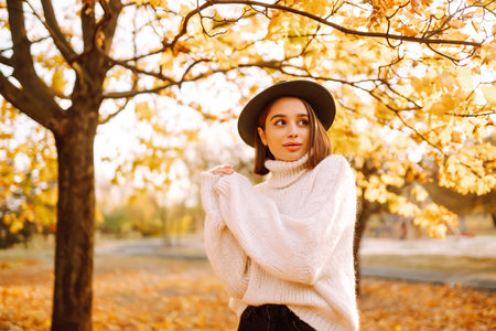 Sunny lifestyle portrait of young stylish woman walking on park, wearing cute trendy hat. fashion concept.の写真素材