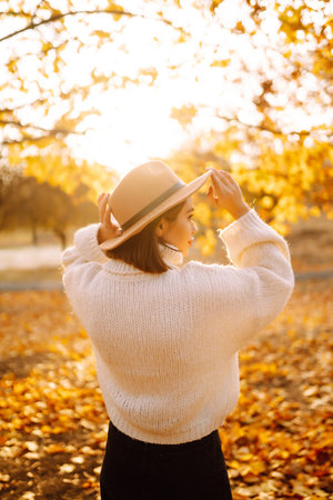 Sunny lifestyle portrait of young stylish woman walking on park, wearing cute trendy hat. fashion concept.の写真素材