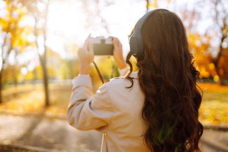 Beautiful woman taking pictures in autumn forest. Woman enjoying autumn weather. lifestyle concept.の写真素材