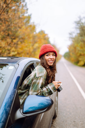 Beautiful woman takes pictures on camera from the car window. Rest, relaxation, lifestyle concept.
