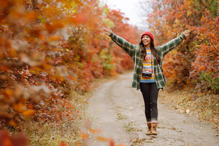 Beautiful woman taking pictures in autumn forest. Smiling woman enjoying autumn weather. lifestyleの写真素材