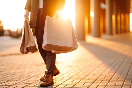 Shopping bags in the hands at sunset. Hand of young man with paper bags with purchases.の写真素材