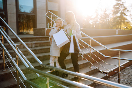 Young mother and little girl with shopping bags after shopping. spring style. consumerism.の写真素材