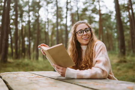 Stylish woman reading a book in the autumn park.の写真素材