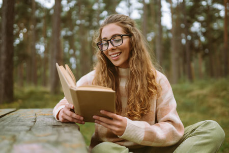 Stylish woman reading a book in the autumn park.の写真素材
