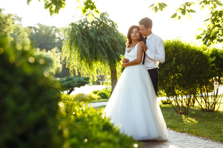 Lovely wedding couple at sunset. Bride, groom in wedding attire with bouquet of flowers. Romantic.の写真素材