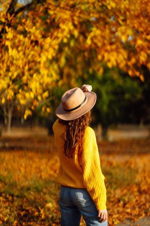 Young woman in a yellow sweater and jeans resting in nature. Fashion, style concept. People, lifestyle.の写真素材
