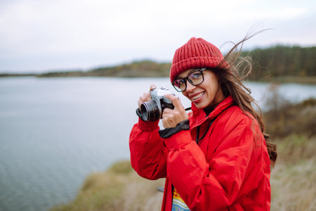 Young woman- tourist taking pictures in autumn forest. Rest, relaxation, tourism, lifestyle concept.の写真素材