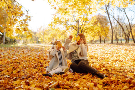Mother and daughter walking in park and enjoying beautiful autumn nature. Childhood, walk, family.の写真素材