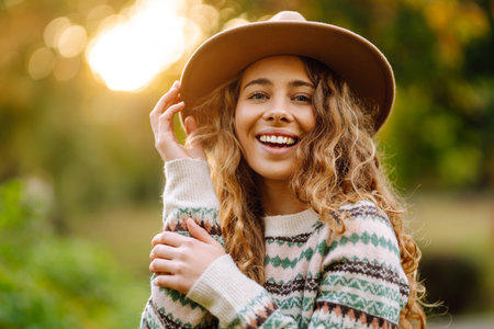 Happy woman in stylish sweater and hat outdoors in autumn park on plaid. Woman enjoys autumn nature.の写真素材