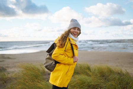 Happy tourist in a yellow jacket enjoying sea landscape at sunset. Traveling, lifestyle, adventure.