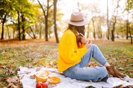 Fall picnic with pumpkin. Stylish woman enjoying autumn weather in the park. autumn harvest.の写真素材