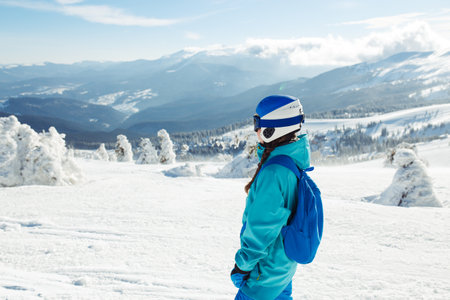 Girl in winter clothes drinking tea on the background of snow-capped mountains on the sunny day.の写真素材