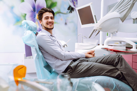 Young man at the dentist's chair during a dental procedure. Overview of dental caries prevention.の写真素材