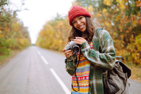 Woman taking pictures in autumn forest. Smiling woman enjoying autumn weather. Relaxation concept.の写真素材
