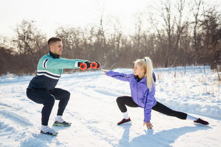 Young couple winter morning exercise at snowy forest. Healthy fitness lifestyle. Sport, Active life.の写真素材