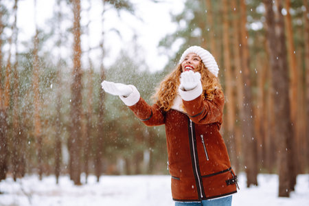 Winter smiling woman stands among snowy trees in winter forest.