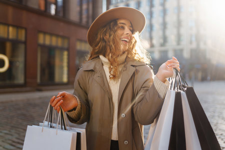 Stylish woman with shopping bags walks through city streets. Spring Style. Lifestyle concept.の写真素材