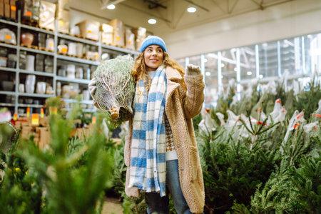 Beautiful young woman buys a Christmas tree at the fair. New Year's holiday conceptの写真素材