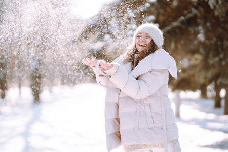 Young woman in winter style clothes walking in the snowy park. Winter fashion, holidays.の写真素材