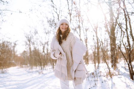 Happy woman in winter style clothes walking in the snowy park. Nature, holidays, travel concept.の写真素材