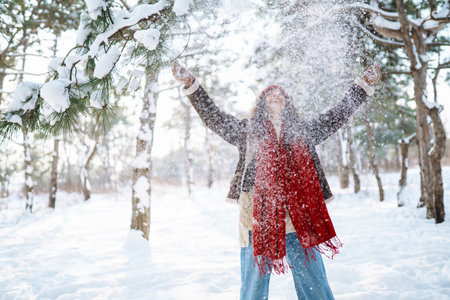 Happy woman standing among snowy trees and enjoying first snow. Holidays, rest, travel conceptの写真素材