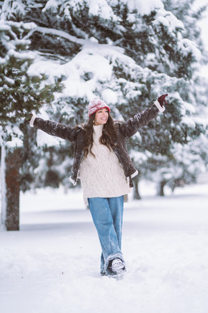 Cheerful young woman celebrating holding sparkles in the winter forest Christmas, new year.