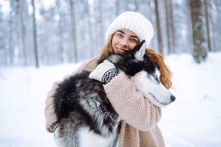 Beautiful young woman plays with her dog in winter forest. First snow Friendship. Outdoor recreationの写真素材