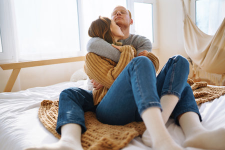 Couple in love relaxing at home on bed while they hug each other. Valentine's Day, holiday concept.