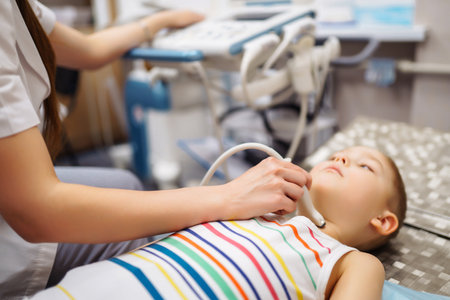 Doctor conducts ultrasound examination of heart, abdominal organs of little boy using equipment.