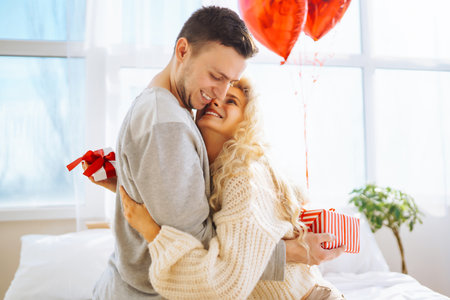Beautiful couple in bedroom decorated with balloons enjoying time together. Concept of relationshipsの写真素材