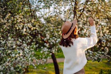 Smiling woman with hat posing in blooming spring park. The concept of relax, travel. fashion style.の写真素材