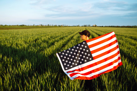 Man hold waving American USA flag. Patriot raise national american flag. Independence Day, 4th July.の写真素材