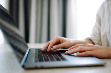 Close-up of woman's hands on a laptop keyboard, typing on modern laptop at home. Freelancing conceptの写真素材