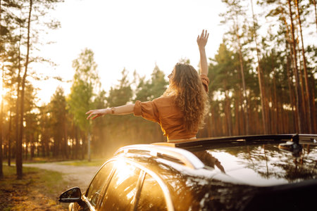 Beautiful traveler woman is resting and enjoying the sunset in the car. Active lifestyle, tourism.