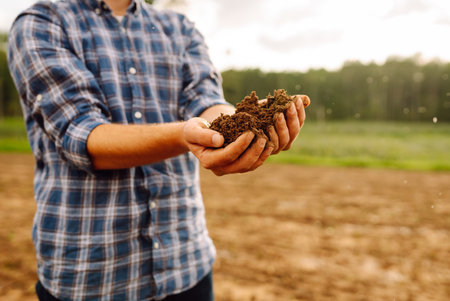 Close-up of a farmer's strong hands on a black field. Concept of gardening, ecology.