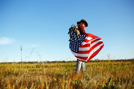 4th of July. American Flag. Traveler with the flag of America. The man in a hat, a backpack, a shirt...