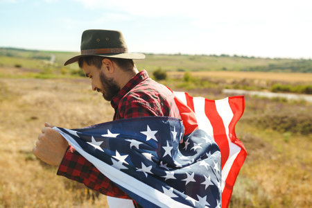 4th of July. American Flag. Traveler with the flag of America. The man in a hat, a backpack, a shirt and jeans.の写真素材