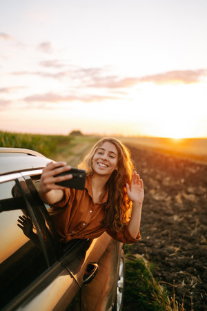 Selfie time. Woman takes selfie in car during road trip. Lifestyle, travel, tourism, active life.の写真素材