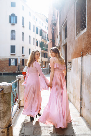 Mother and daughter are walking in sunny Venice in soft pink dresses. Concept of active lifestyle.の写真素材