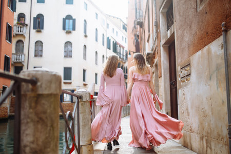 Mother and daughter are walking in sunny Venice in soft pink dresses. Concept of active lifestyle.の写真素材
