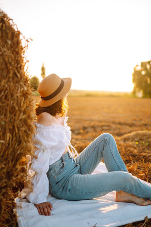 Happy woman near haystack at sunset. Fashion concept. Nature, vacation, relax and lifestyle.の写真素材