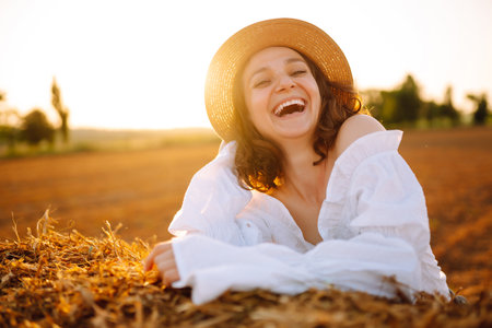 Happy woman near haystack at sunset. Fashion concept. Nature, vacation, relax and lifestyle.の写真素材