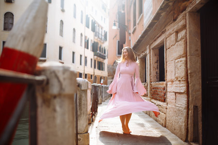 Portrait of stylish woman in pink dress, walks through sunny streets of Venice. Travel concept.の写真素材