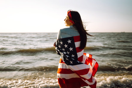 View from the back young brunette female person holding national American flag.の写真素材